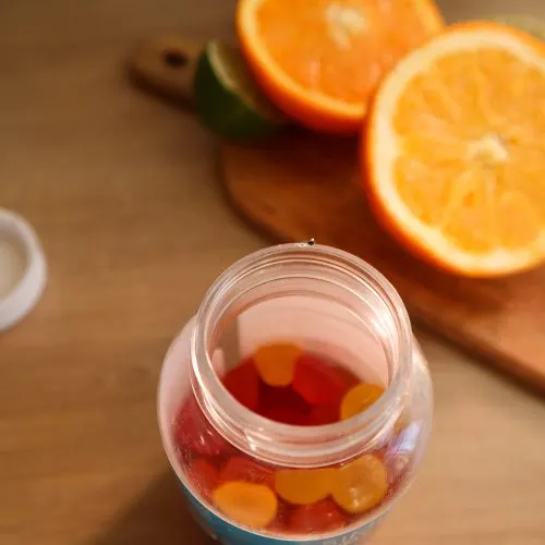 maria-kozyr-KQBX7YTcGuc-unsplash A jar of vitamin gummies beside fresh oranges — dietary supplements