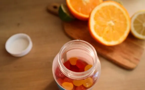 maria-kozyr-KQBX7YTcGuc-unsplash | Tel Aviv Doctor A jar of vitamin gummies beside fresh oranges — dietary supplements